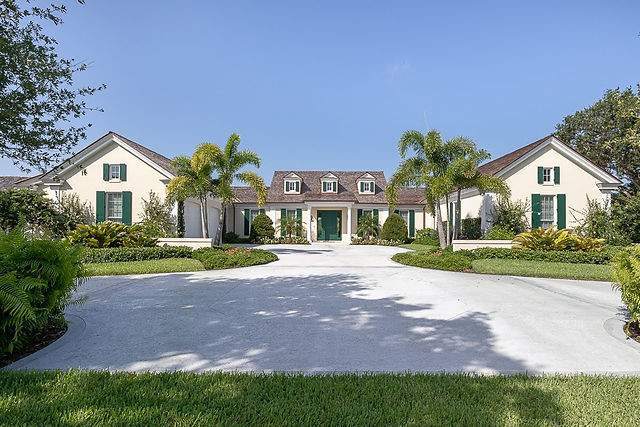 Large home with long driveway and green colonial shutters