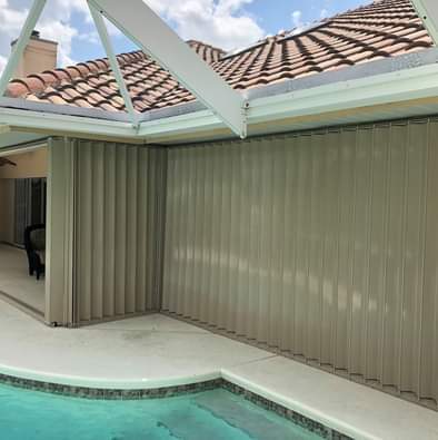 Accordion shutters covering windows around pool deck