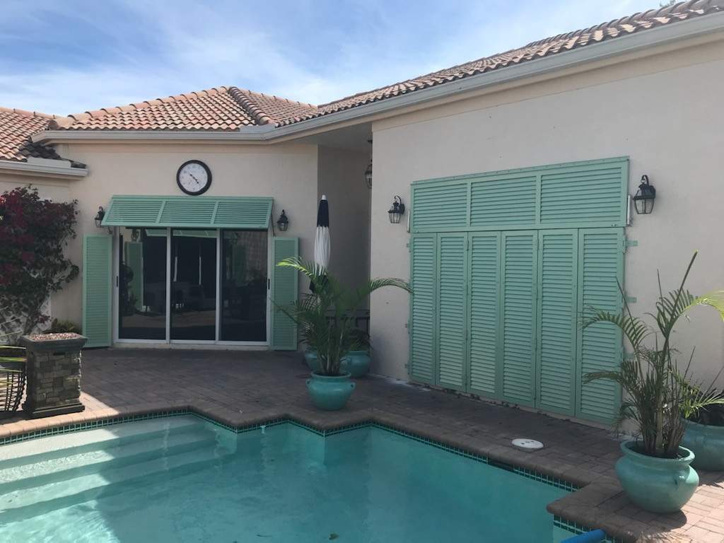 Closed teal bahama shutters on pool deck