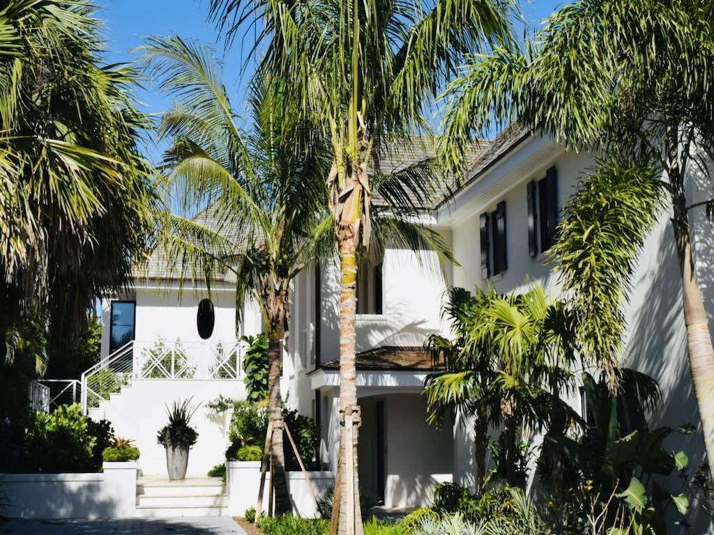 custom railing around off white house with tall palm trees in front