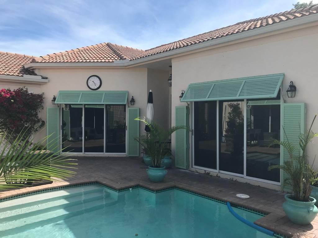 Teal bahama shutters on pool deck showing steps down into the pool