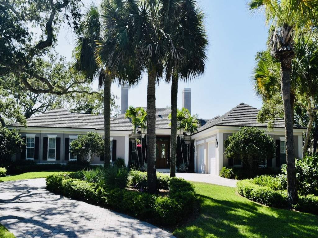 black colonial shutters on a gray house with tall palm trees in the front yard