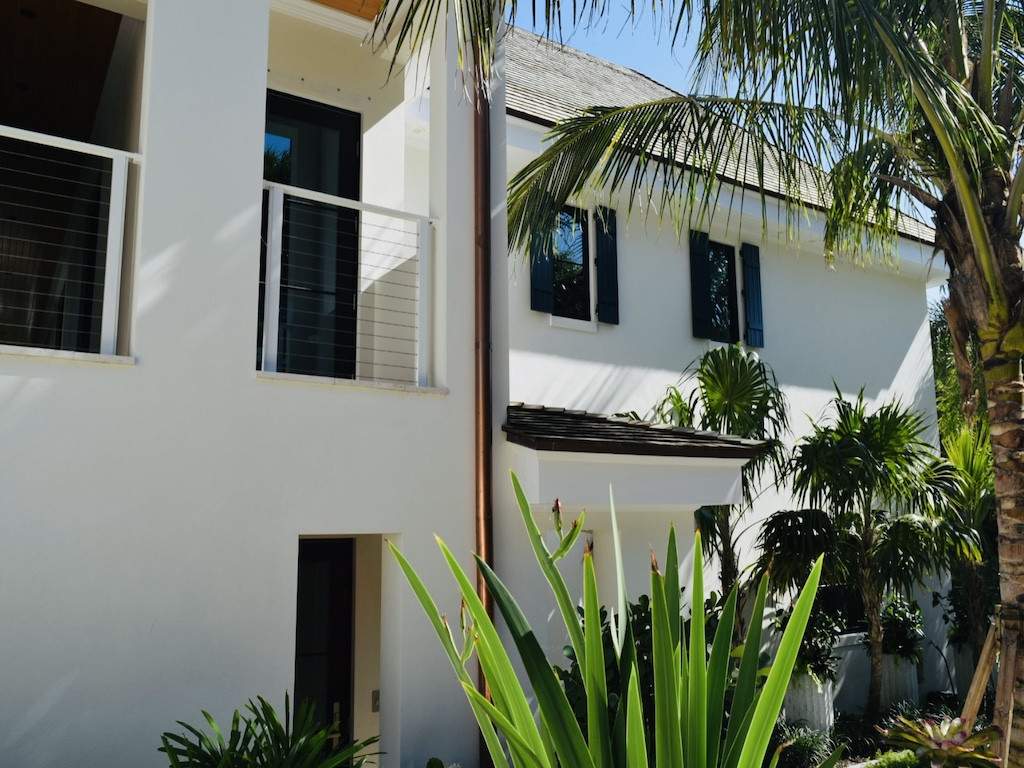 black colonial shutters on cream colored house with palm trees near the window