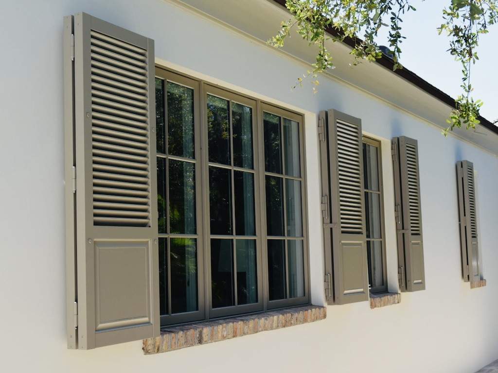 medium brown colonial shutters on an off white house with brick window sills